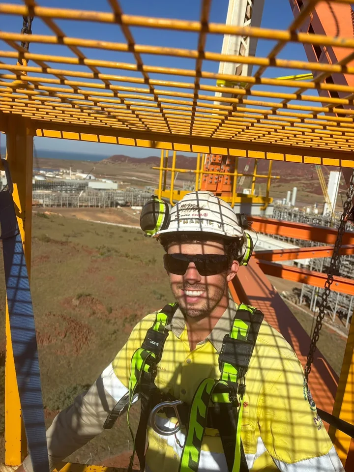 Working at height in a harness on scaffolding overlooking a processing plant
