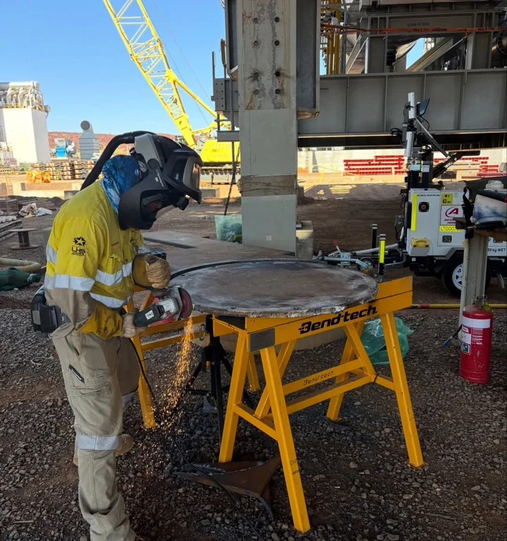 Grinding steel on a fabrication table at a mine workshop